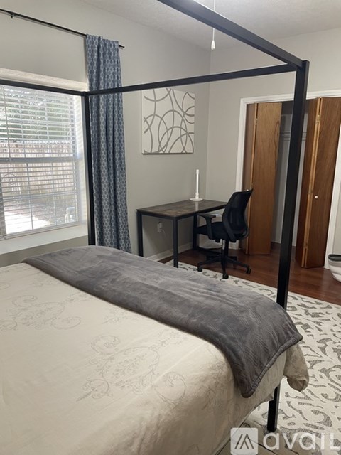 A bedroom with a four poster bed and a desk.