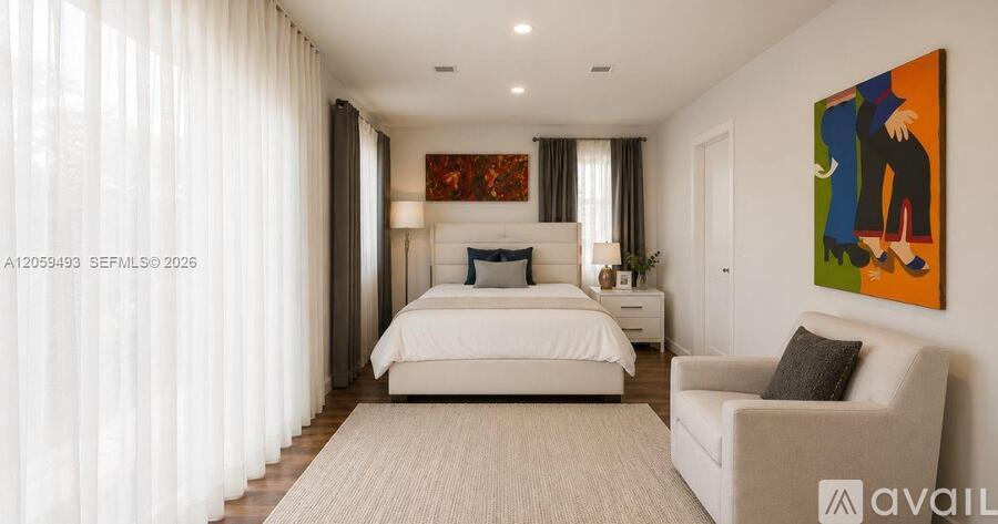 A bedroom with a large bed, a chair, and a painting on the wall.