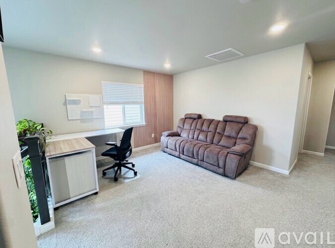 A room with a brown couch, a black chair, and a small table with a plant on it.