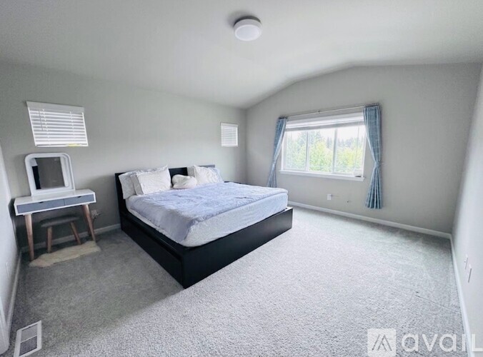 A bedroom with a bed, desk, and window.