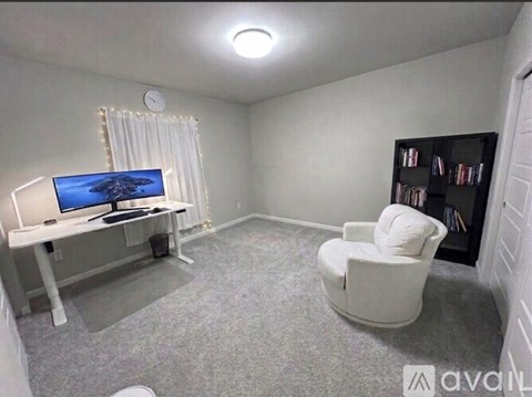 A living room with a television, a chair, and a bookshelf.