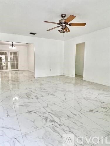 A spacious room with a ceiling fan and marble flooring.