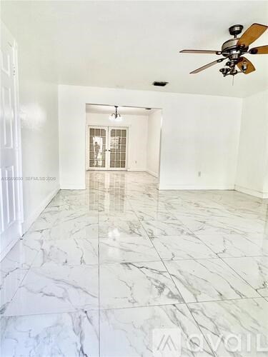 A spacious room with a marble floor and a ceiling fan.