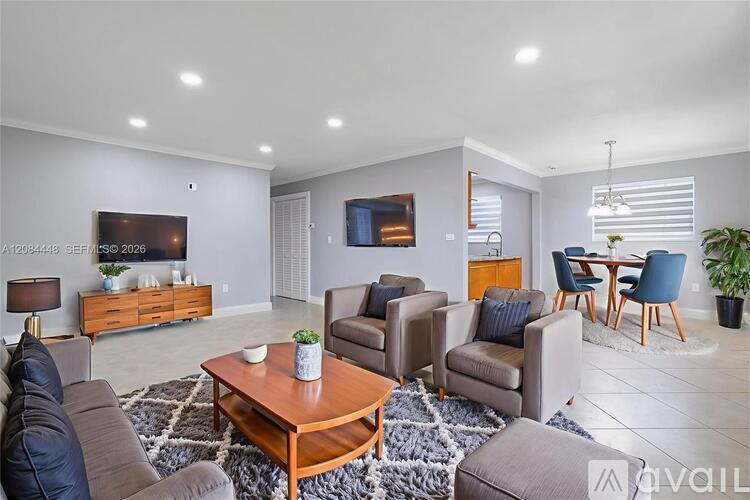 A living room with a brown sofa, a wooden coffee table, and a TV mounted on the wall.