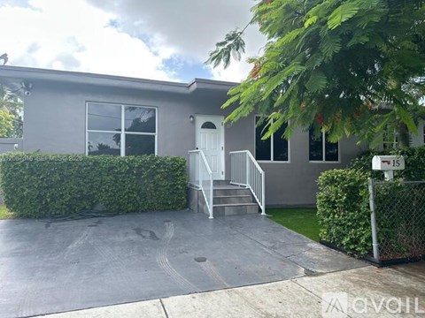 A grey house with a white door and a white fence.