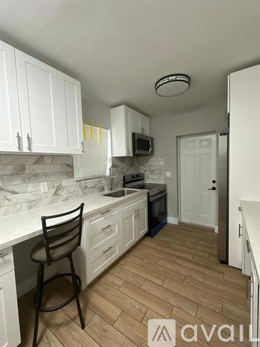 A kitchen with white cabinets and a wooden floor.