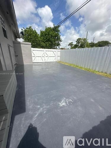 A concrete surface with a fence and trees in the background.