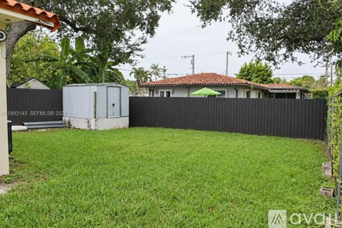 A backyard with a black fence and a green lawn.