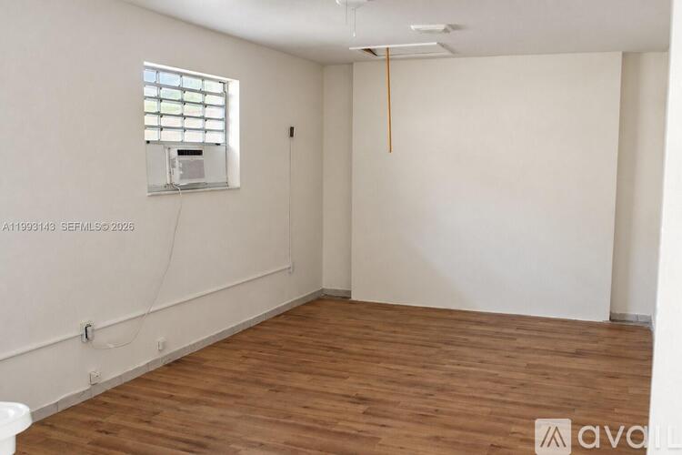 A room with wooden flooring and a window with blinds.