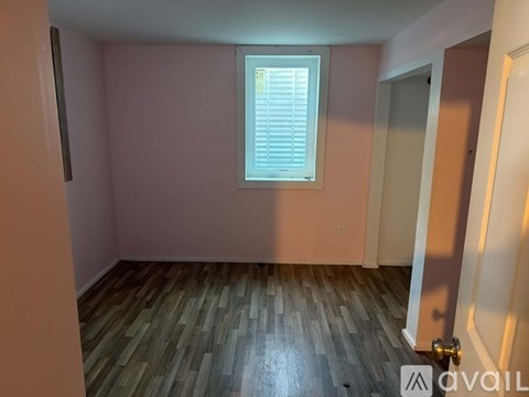A room with wooden flooring and a window with blinds.