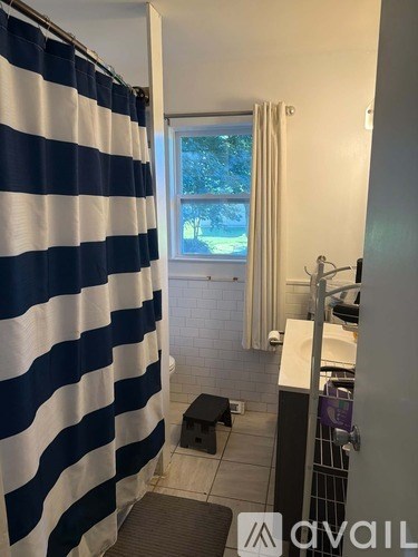 A bathroom with a striped shower curtain and a window.
