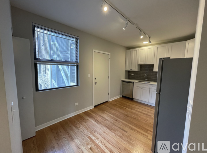 A spacious room with wooden flooring and a large window.