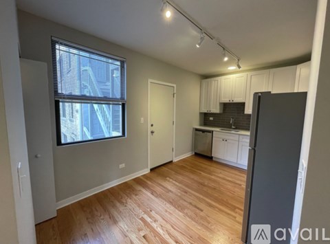 A spacious room with wooden flooring and a large window.