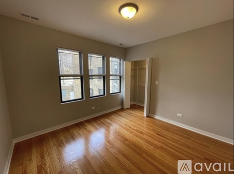 A room with wooden floors and a window with a view of a building outside.