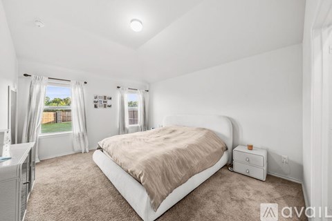 A bedroom with a large bed and a window with curtains.