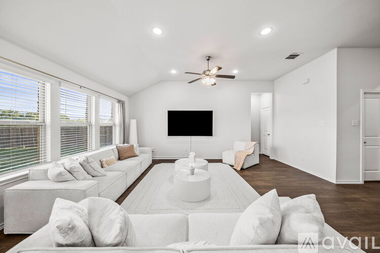 A living room with a white couch and a flat screen TV mounted on the wall.