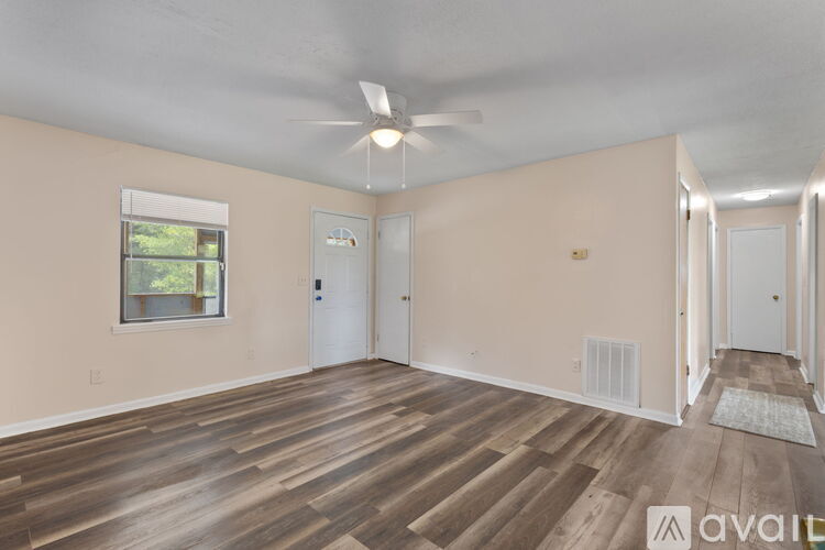 A spacious room with wooden flooring and a ceiling fan.