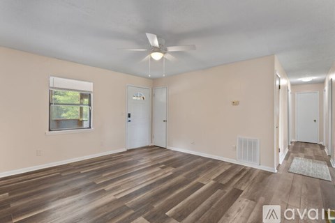 A spacious room with wooden flooring and a ceiling fan.