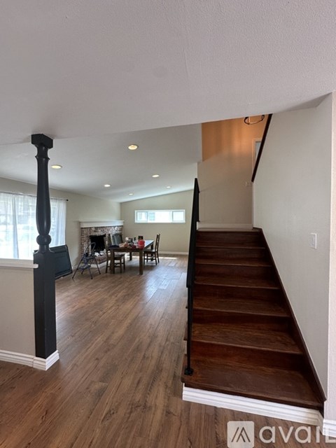 A living room with a dining table and chairs is visible from the stairs.