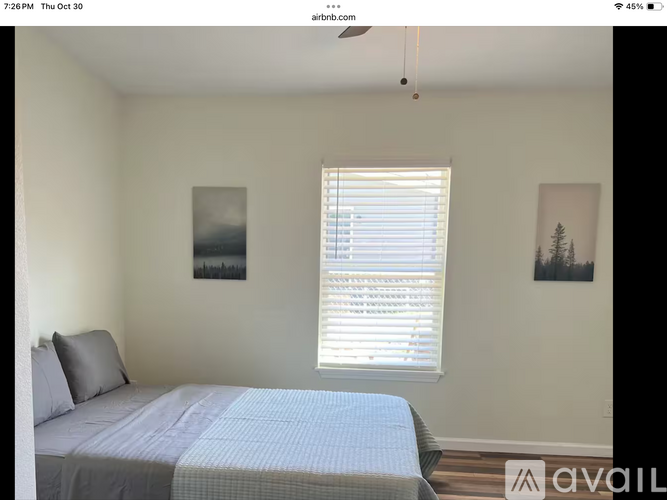 A bedroom with a bed, a ceiling fan, and two pictures on the wall.