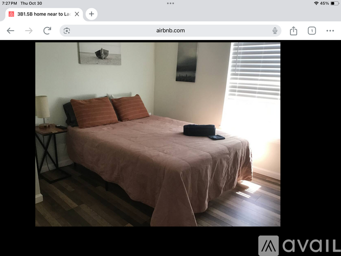 A bedroom with a bed covered in a pink sheet and two pillows.