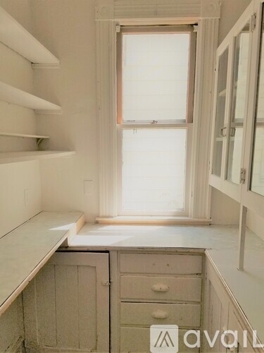 A white kitchen with a window and drawers.