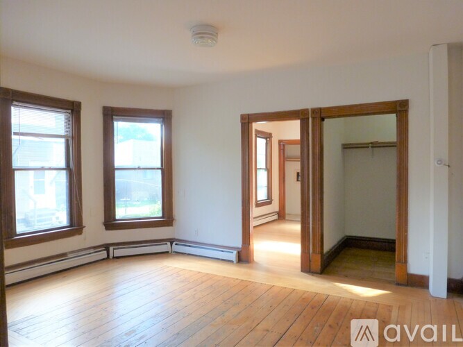 A room with wooden floors and three windows.
