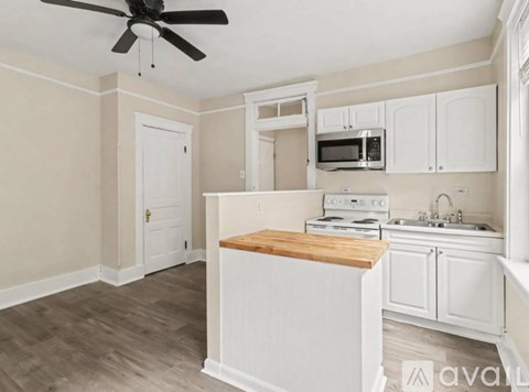 A kitchen with white cabinets and a wooden island.