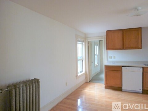 A room with a wood floor and a white wall with a window and a door.