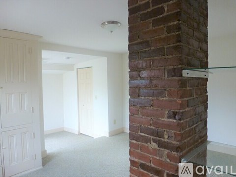 A room with a brick pillar and a carpet floor.
