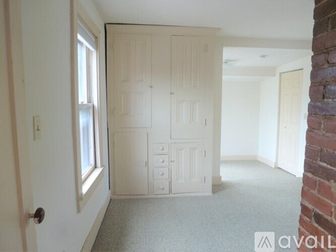 A room with a white door and a window on the left.