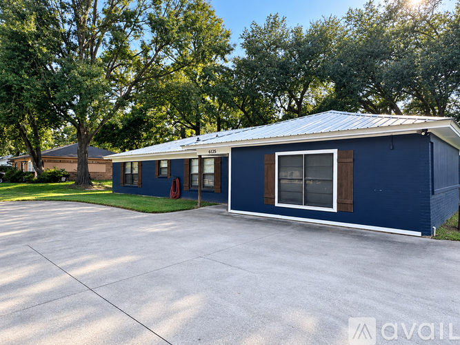 A blue house with a white roof and a driveway in front.