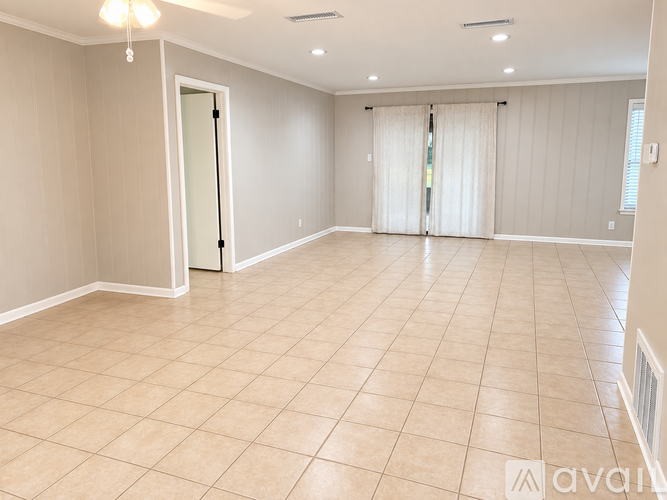 A spacious room with beige tiled flooring and white walls.