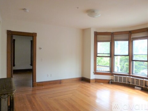 A room with a wooden floor and a window with a view of trees.