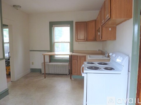 A kitchen with a white stove and wooden cabinets.
