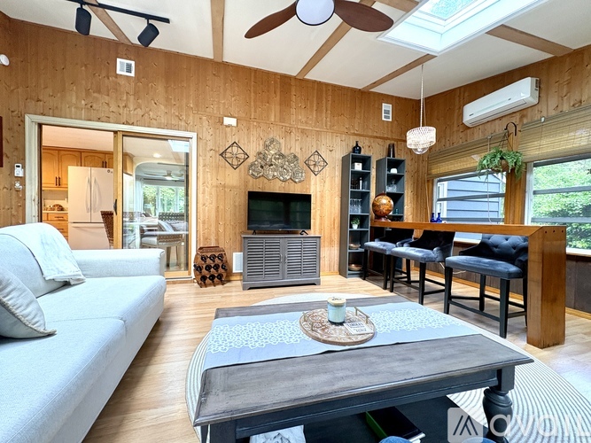 A living room with a grey couch, a wooden coffee table, and a television.