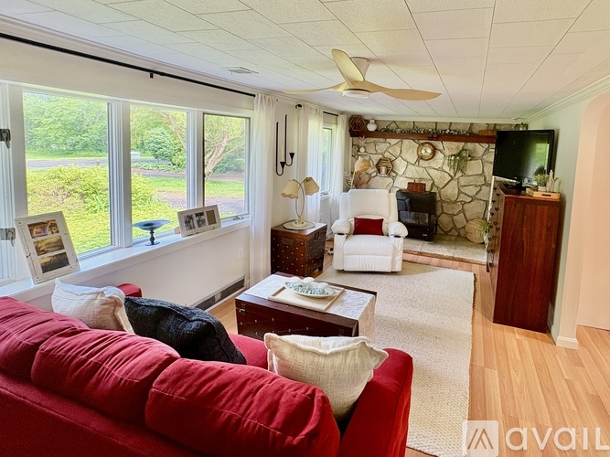 A living room with a red couch and a fan on the ceiling.