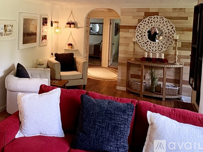 A living room with a red couch and a white chair.