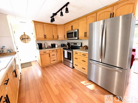 A kitchen with wooden cabinets and a stainless steel refrigerator.
