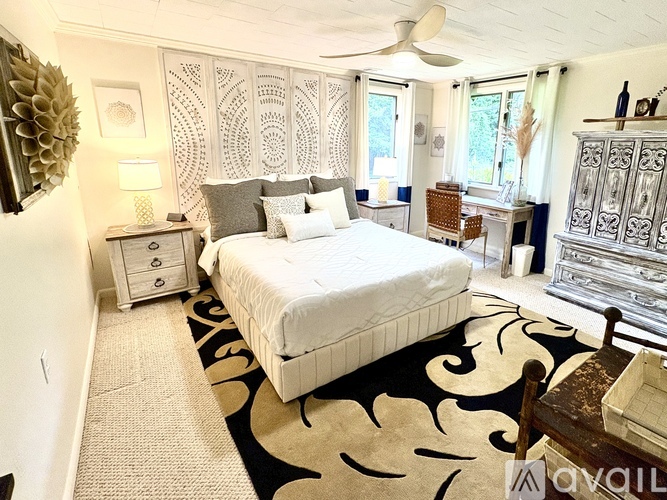 A bedroom with a large bed and a patterned rug.