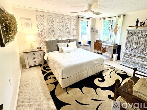 A bedroom with a large bed and a patterned rug.