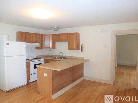 A kitchen with white appliances and wooden cabinets.