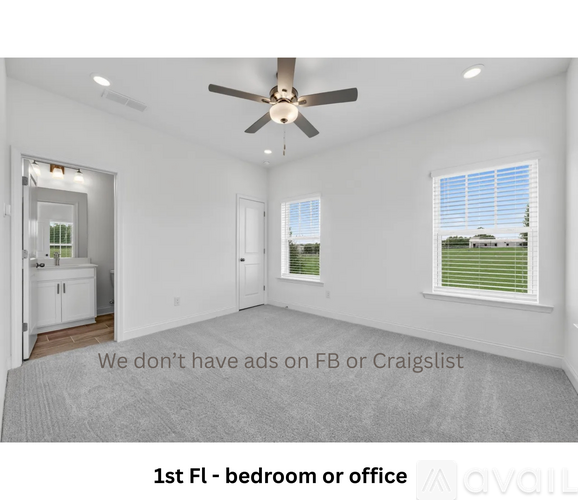 A spacious room with a ceiling fan and a view of a green lawn through the window.