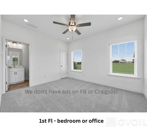 A spacious room with a ceiling fan and a view of a green lawn through the window.