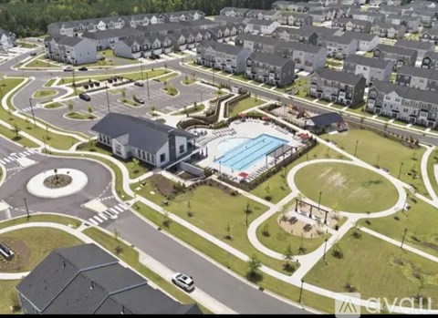 A bird's eye view of a residential area with a swimming pool and a roundabout.