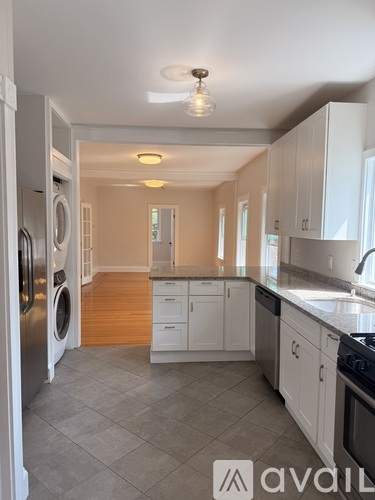A kitchen with white cabinets and a washer and dryer in the corner.