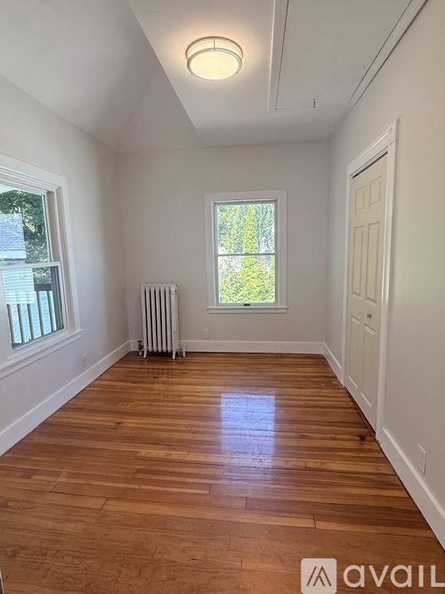 A room with wooden floors and a window with a view of trees.