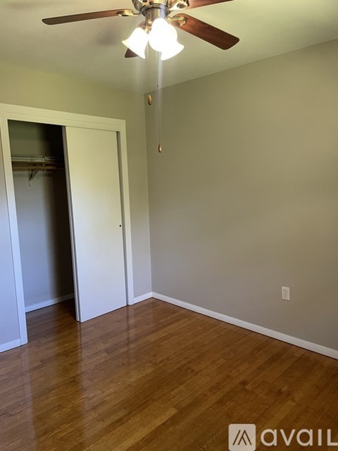 A room with a ceiling fan and wooden floors.