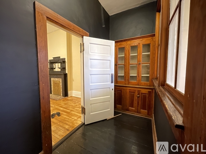 A room with a white door and wooden cabinets.
