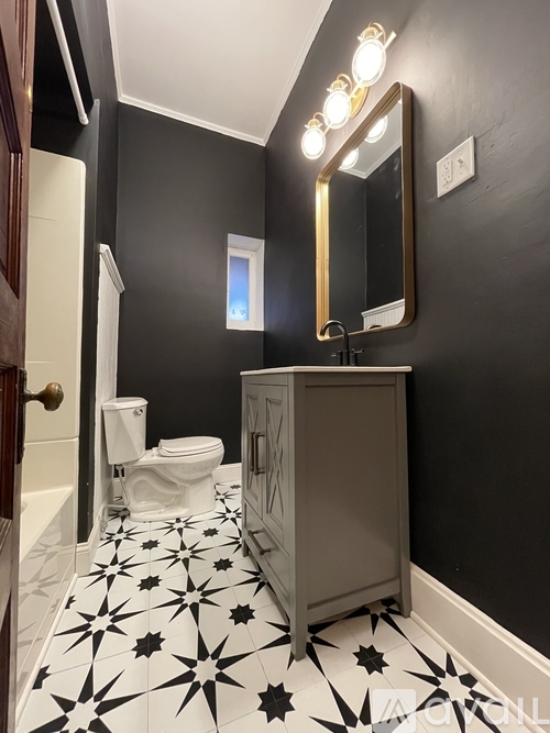 A bathroom with a star patterned floor and a wooden door.